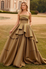 Woman wearing a gold strapless prom gown with ruffled layers.