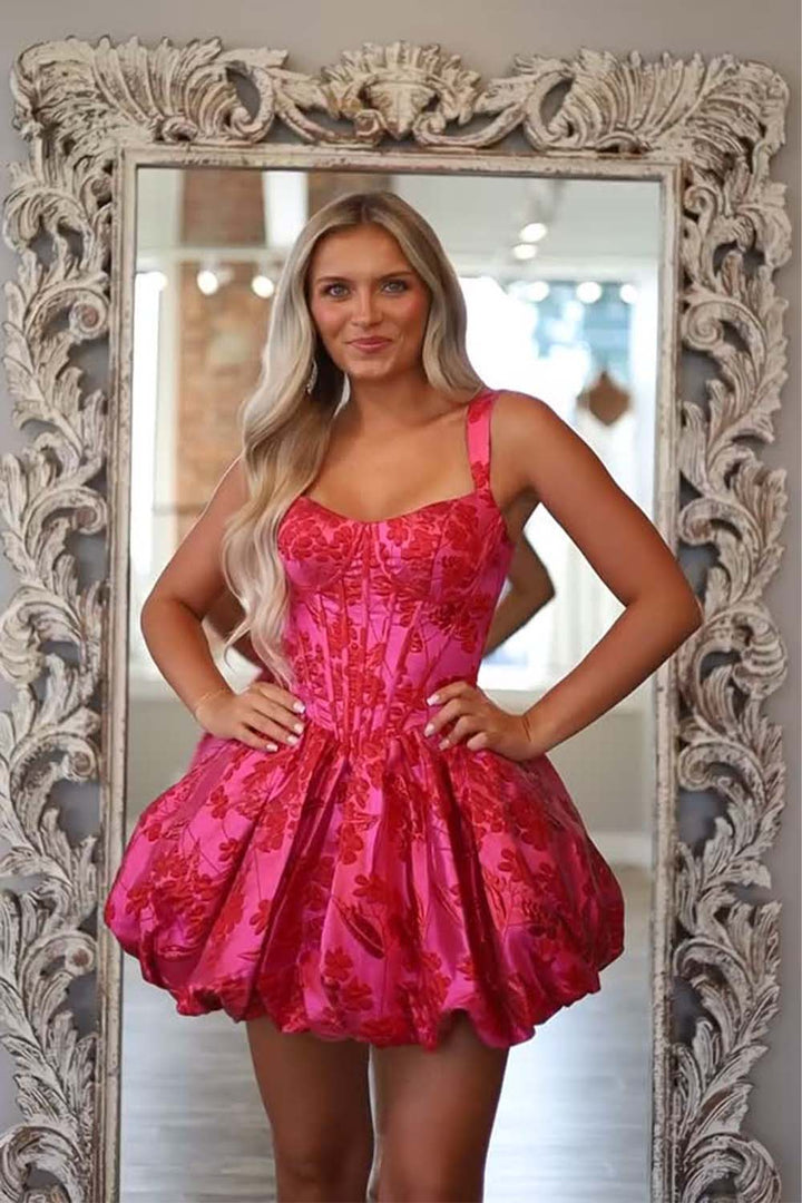 Woman in a pink floral dress standing in front of an ornate mirror.